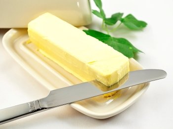 butter on white butterdish with knife , close up