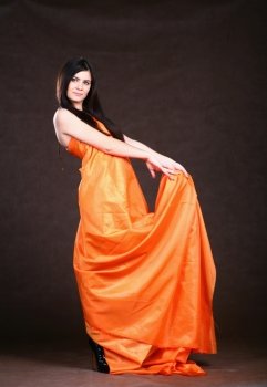 Attractive girl in orange fabric studio shot over brown background