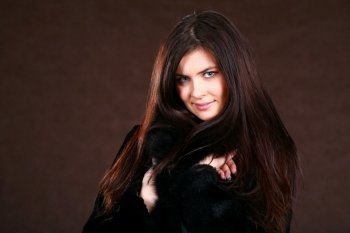 attracive young woman in a fur coat  brown background