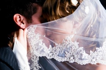 just married couple is kissing under veil