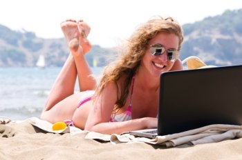 happy woman is working on laptop on beach