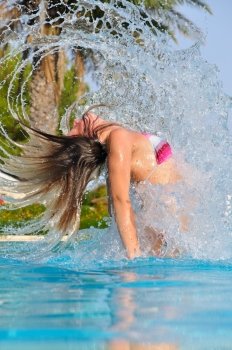 slim woman is spectacularly jumping out of pool and shaking hair