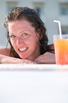 close up of pretty woman with wet hair in swimming pool with cocktail