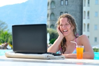 beautiful woman is using laptop in the swimming pool