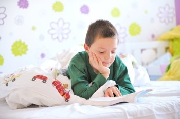 Young boy in his bed reading a book