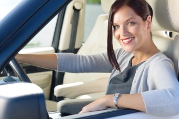 Attractive elegant businesswoman driving luxury car smiling at camera