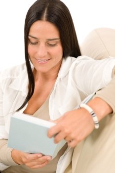 Happy mid-aged woman read book sitting on couch