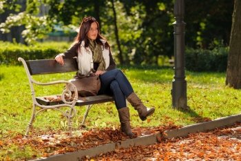 Autumn fashion outfit attractive woman  sitting on park bench sunset