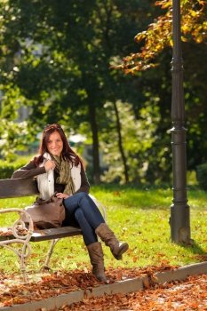 Autumn fashion outfit attractive woman  sitting on park bench sunset