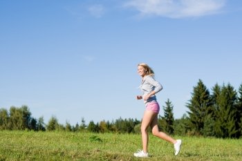 Sportive jogging young happy woman meadows blue summer sky