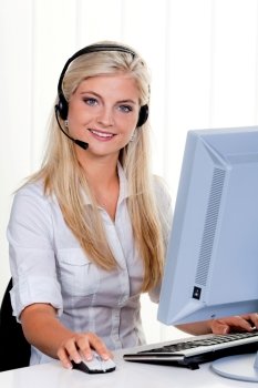young woman at computer with headset and hotline.