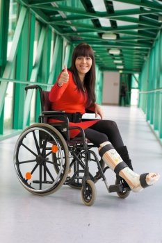 a young woman with a broken leg. leg in plaster and wheelchair