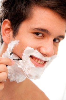 Junger Mann rasiert sich mit Rasierklinge Und Rasierschaum im Badezimmer