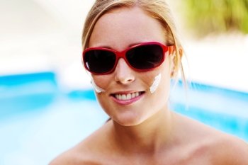 young woman with sunglasses in the summer and sun cream