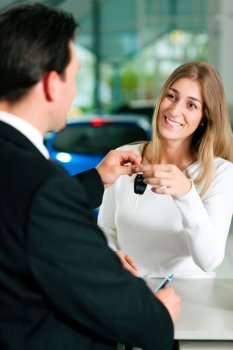 Woman at a car dealership buying an auto, the sales rep giving her the key