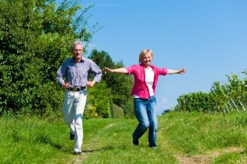 Visibly happy mature or senior couple outdoors having a walk in a playful way 