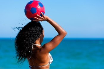 Young woman on the beach playing soccer in her vacation