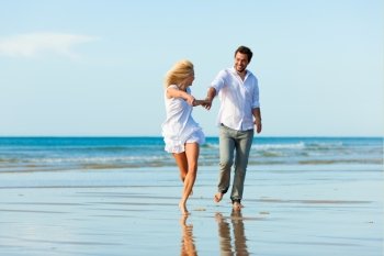 Couple on the beach in white clothing running down, they might be on vacation or even honeymoon