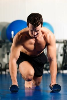Very strong and muscular man exercising by starting pushups in a gym