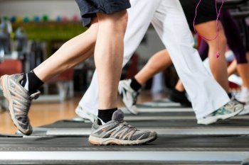 Running on treadmill in gym or fitness club - group of women and men - only legs to be seen - exercising to gain more fitness