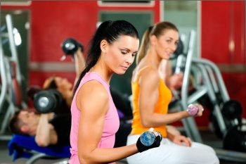 People in gym or fitness club exercising with weights together