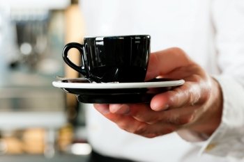 Coffeeshop - barista presents coffee or cappuccino; close-up on mug