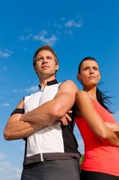 Fitness - Young sportive couple in front of a blue sky on a beautiful summer day outdoors
