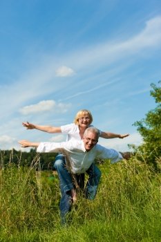 Happy mature couple - senior people (man and woman) already retired - having fun in summer in nature
