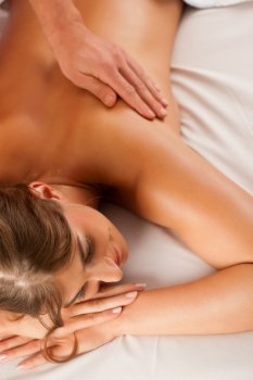 Woman enjoying a wellness back massage in a spa, she is very relaxed (close-up)