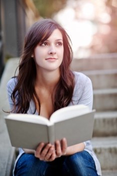 A shot of a smiling college student reading a book