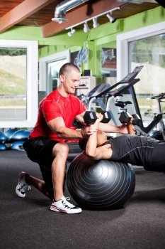 A shot of a male personal trainer assisting a woman lifting weights