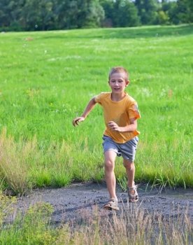 Small boy running on green meadow, summertime