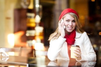 A shot of a beautiful caucasian woman talking on the phone at a cafe