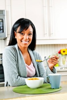 Smiling black woman having breakfast in modern kitchen interior