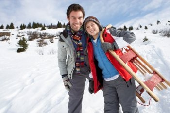 Young Father And Son In Snow With Sled