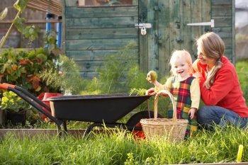 Woman working on allotment with child