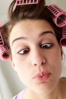Teenage girl with hair in curlers pulling a face