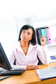 Young black business woman thinking at desk in office