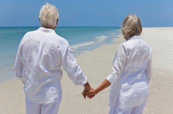 Senior Couple Holding Hands & Looking To Sea on Beach