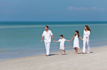 Mother, Father and Children Family Walking Holding Hands On Beach