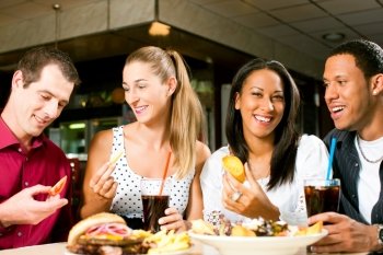 Friends - one couple is African American - eating hamburger and drinking soda in a fast food diner; focus on the meal