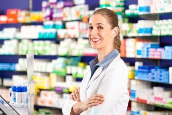 Female pharmacist is standing in her drugstore behind the counter