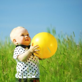 little boy play in green grass with yellow ball