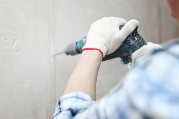 man worker hammer drills wall