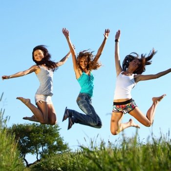 girlfriends jump in green grass field