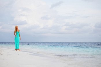 woman in a blue dress on the ocean coast