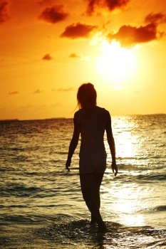 happy woman standing on a sunset in ocean waves