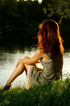 Girl sitting on tha bank of forest river