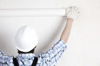 worker attaching wallpaper to wall