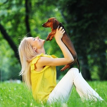 woman dachshund in her arms on grass